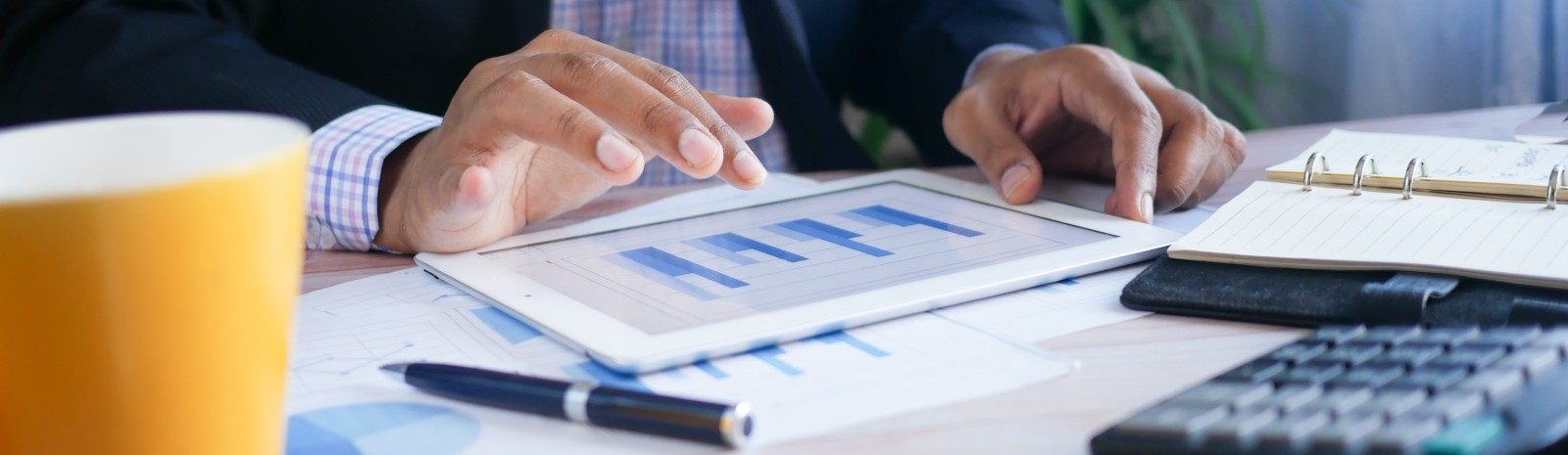 Businessperson sitting at a desk working on finances on a tablet.